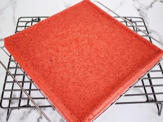 红丝绒奶油蛋糕卷,烤好马上取出震一震，然后倒扣在烤网上，轻轻撕掉油纸晾至余温