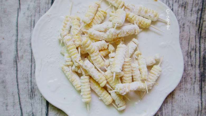 牙签玉米,拌匀，让每粒玉米上都沾上粉，然后空出多余粉即可