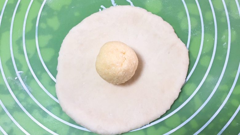 椰蓉心形面包,椰蓉馅儿分成四个剂子，滚圆。将面团剂子擀成圆饼，椰蓉馅儿放中间。