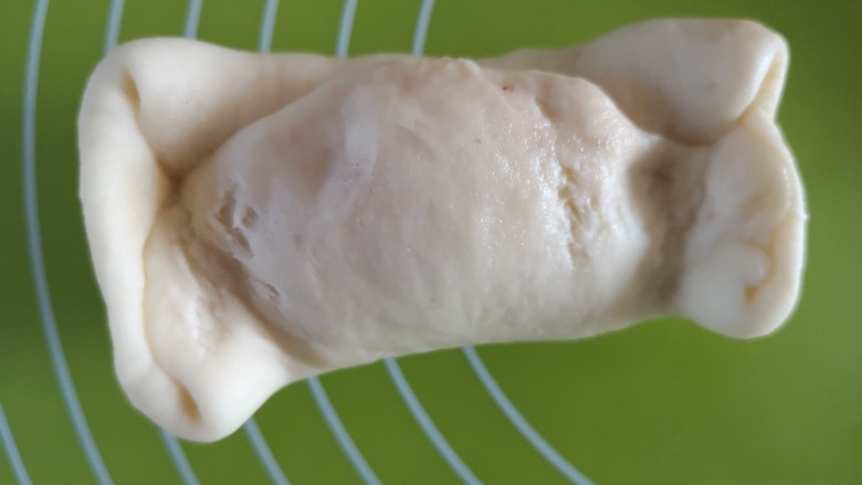 芝麻蜜豆面包,将两端的口收紧然后向中间折叠并捏紧