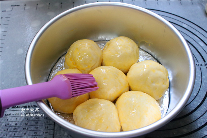 芝麻馅香软小餐包,将发酵好的面包取出，表面刷一层蛋黄液，再撒上一层粗糖；
