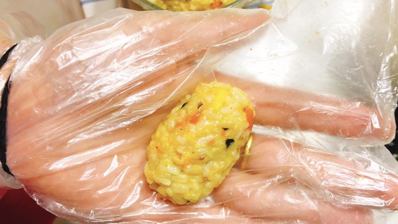 咖喱海苔什锦饭团,保鲜袋套在手上，抓一点饭团，揉成小小的椭圆形。