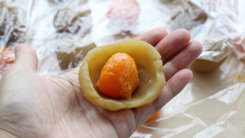 蛋黄莲蓉月饼,取一个莲蓉馅放在手心压扁，然后放上蛋黄