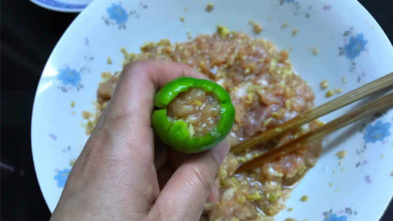  虎皮青椒酿肉,然后取一个去了籽的青椒，用筷子把肉馅塞进青椒中。