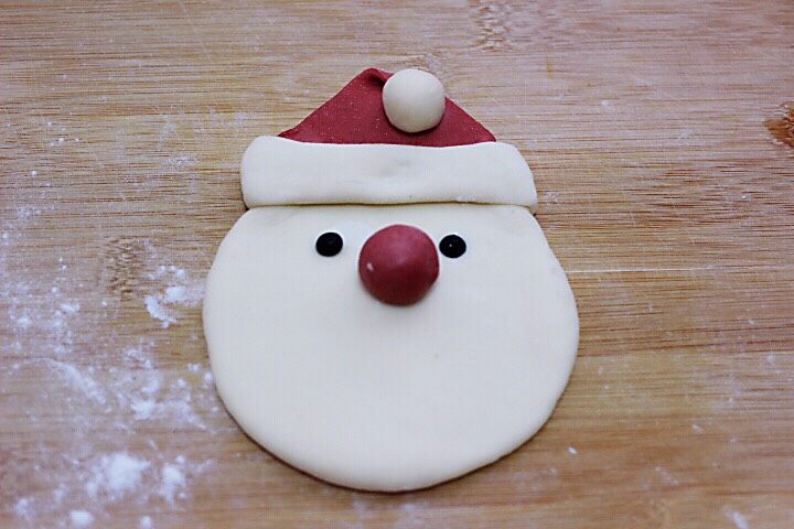 十味  萌萌哒的圣诞老人馒头,把搓好的小面蛋压在折过来的地方、如图，把红色的小圆蛋放在脸部的合适位置、再把黑豆做成眼睛。