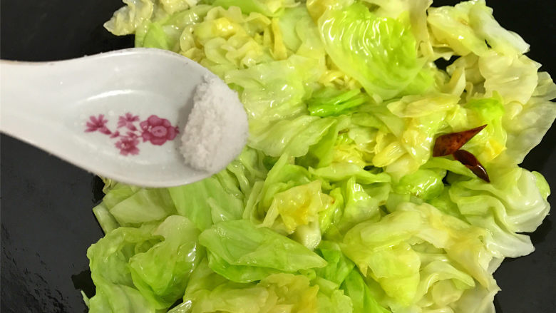 炝炒手撕包菜,快速翻炒均匀，让菜叶都沾上油汁后，加入适量的盐。
