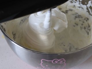 奶香浓郁牛轧糖（熬糖版），越嚼越香,立即倒入打发好的蛋白中（气温低的话，蛋白盆需要底下再隔个热水盆）。同时打蛋器，继续搅打，糖水需要倒在蛋白上，不要碰到盆壁和打蛋头。打完糖水，搅打均匀，倒入保温的黄油液，搅打均匀。