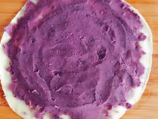 紫薯鸡蛋卷,平铺在案板上 将紫薯泥均匀涂抹在饼上