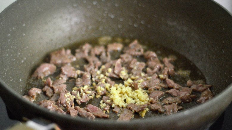 黑椒牛肉杏鲍菇,快速划炒至牛肉变色后放入姜末炒匀