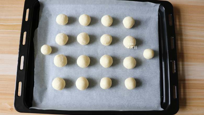 蛋白椰丝球,揪一小团揉成圆球形，一一放在铺了油纸的烤盘上;