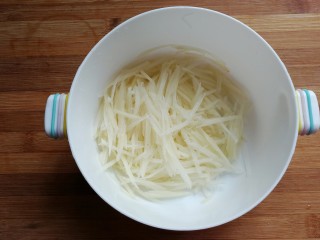 黄金芝士培根土豆饼,土豆一个洗净去皮，然后擦成细丝，再过清水冲洗一下沥干。
