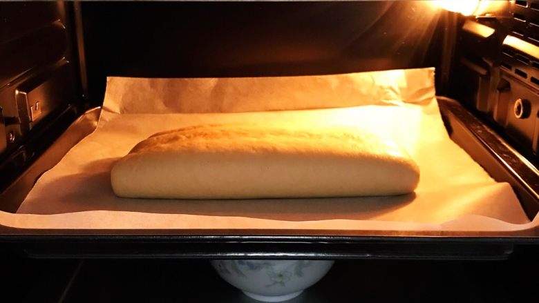 红曲双色椰浆面包,把面团放入烤箱内进行二发，开启烤箱发酵功能，可设定发酵温度35度，在烤箱下层放碗温水增加湿度。