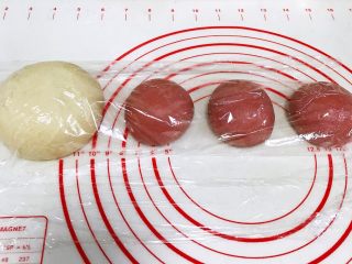 红曲双色椰浆面包,把发酵好的面团进行排气，再次滚圆松弛15分钟，依然是要盖好保鲜膜。