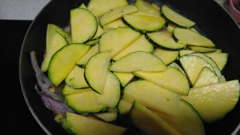 南瓜菜拌火龙果手擀面,锅中放入少许油，放入蒜、姜、洋葱炒香，放入南瓜片。