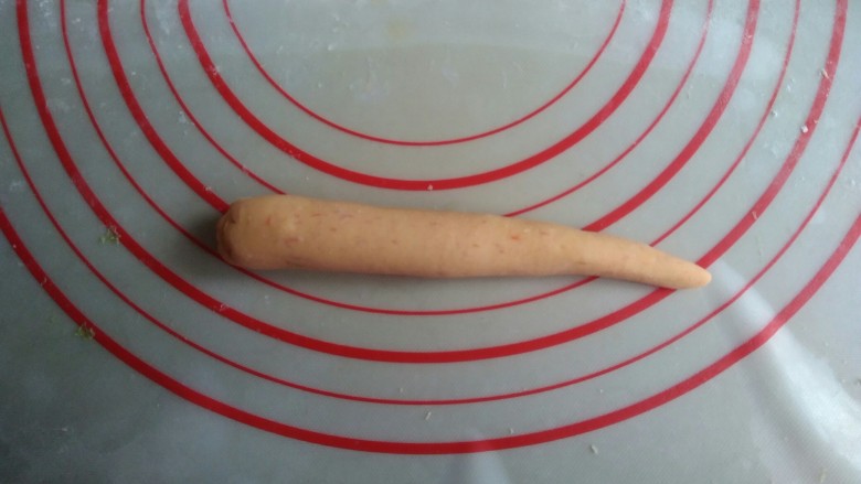 象形胡萝卜馒头,分成每个40-45克左右的小面团，将面团搓长一点，一边大一边小，搓出胡萝卜的外形。