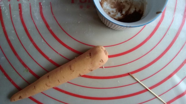 象形胡萝卜馒头,可可粉和一丁点水拌一下，用牙签沾点可可液，在胡萝卜身上划出数道纹路。