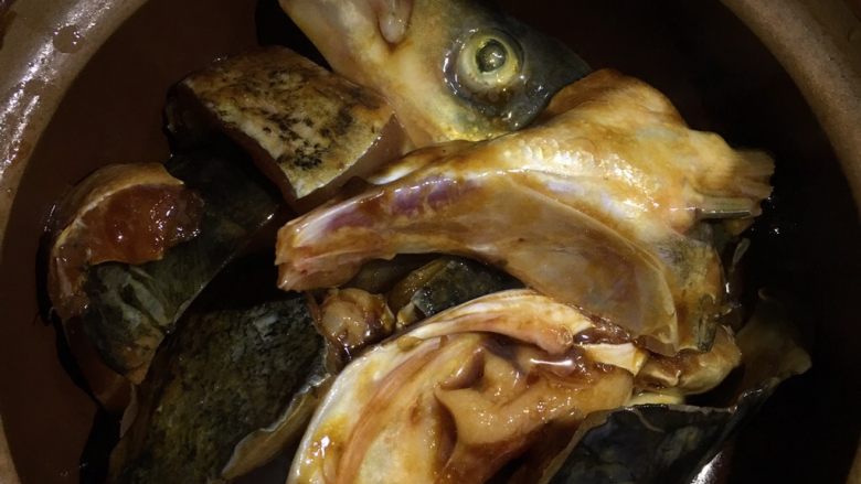 砂锅鱼头,炒香大蒜和姜后一块一块地加入鱼头盖上盖子慢火焗15分钟