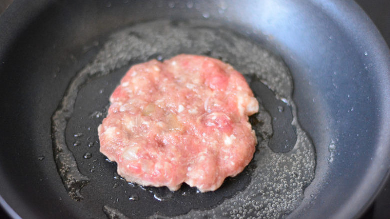 美式牛肉汉堡,平底锅放少量的食用油，烧热，然后放入肉饼，大火先把两面各煎1分钟，让表面熟透，转最小火，盖上锅盖，焖上3-5分钟，让里面的肉馅熟透
