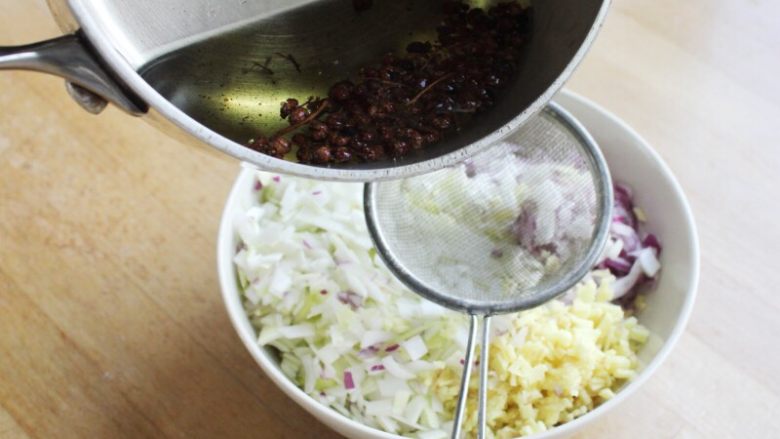 十味 多汁猪肉煎饺,将切好的大葱、洋葱和姜放到小碗里，将烧热的花椒油浇到上面。