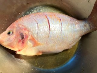 红烧鱼,把鱼放入大碗里，放入1g盐，10g料酒，用手抹匀，腌制20分钟。