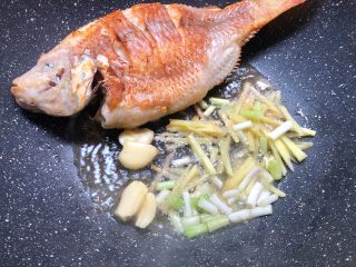 红烧鱼,把鱼俩面煎好，把鱼拨到一边，放入姜丝、葱白、蒜瓣爆香