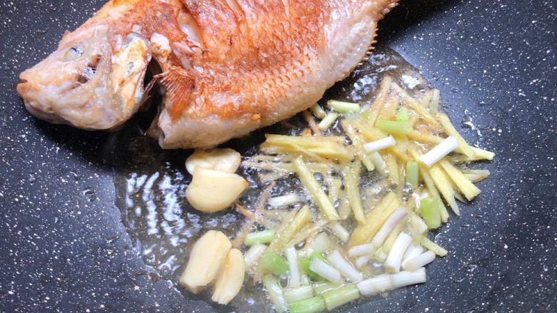 红烧鱼,把鱼俩面煎好，把鱼拨到一边，放入姜丝、葱白、蒜瓣爆香