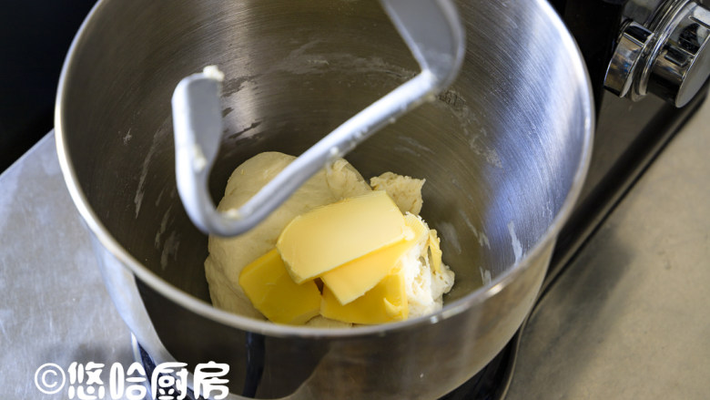 玉米芝士面包,开启厨师机，先用低速揉成团，再用中速搅拌5分钟，放入室温下软化的黄油，继续搅打面团。