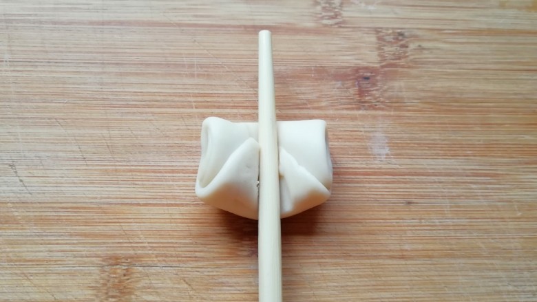 紫薯馅老婆饼, 取一个松弛好的卷，用筷子从中间压一下，让两头翘起。