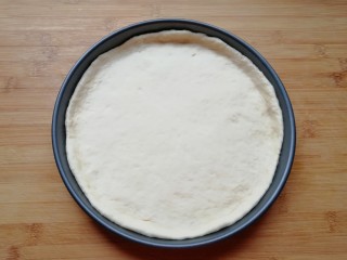 火腿肠披萨,发酵好的面团揉光排气，擀成一张比模具大一些的面饼，放进披萨盘里面，用手把大出来的部分压实，使其贴在披萨盘的边上。