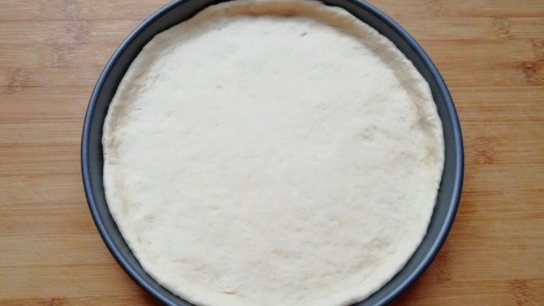 火腿肠披萨,发酵好的面团揉光排气，擀成一张比模具大一些的面饼，放进披萨盘里面，用手把大出来的部分压实，使其贴在披萨盘的边上。