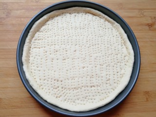 火腿肠披萨,用叉子扎满小孔，防止饼皮在烤制的过程中中间凸起，做好的饼底静置15-20分钟进行第二次发酵。