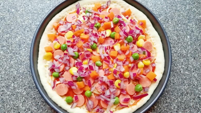 火腿肠披萨,放上青豆、玉米粒和胡萝卜，撒上洋葱。