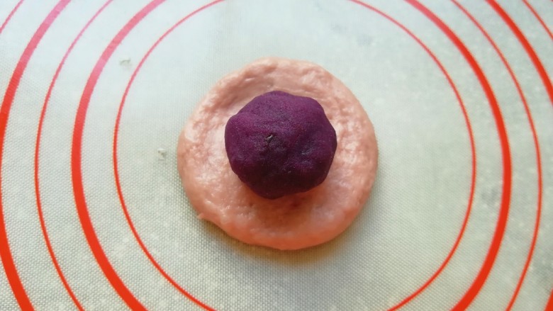 紫薯小餐包,取一个面包面团压扁，放上紫薯馅包好收紧口。
