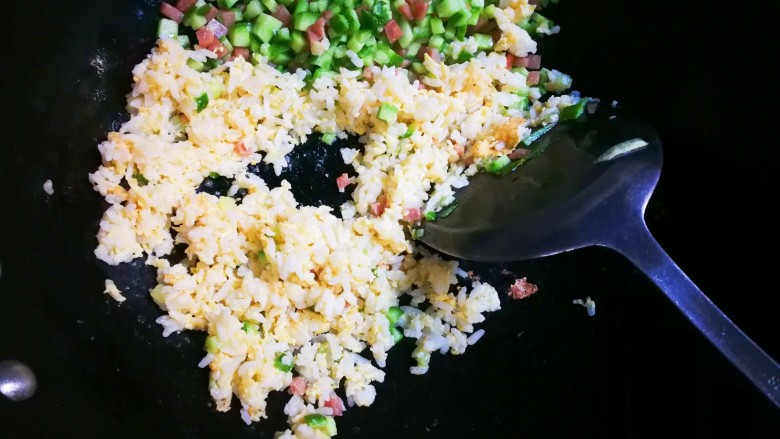 十味  午餐肉黄瓜蛋炒饭,将午餐肉黄瓜推到锅一边，放入拌上蛋液的米饭，翻炒至熟