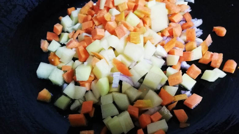 咖喱玉米土豆胡萝卜,将胡萝卜丁，土豆丁，毛葱放入锅内，大火翻炒几下，改小火。