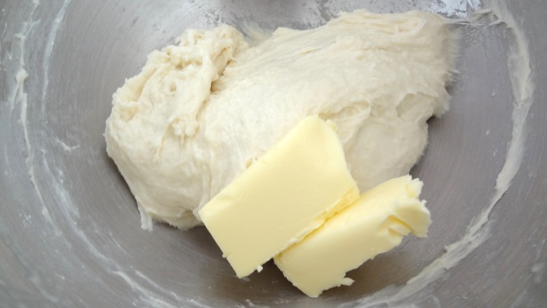 辫子酥粒面包,加入软化好的黄油开始启动低速搅打，黄油混合进去后高速搅打至黄油完全混合