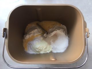 双色牛角酥,面包桶内加入高筋面粉，奶粉，全蛋液，细砂糖跟酵母 