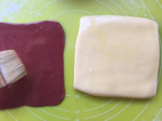 双色牛角酥,用毛刷在面片表层刷上一层黄油液，两色颜色的面片都刷 