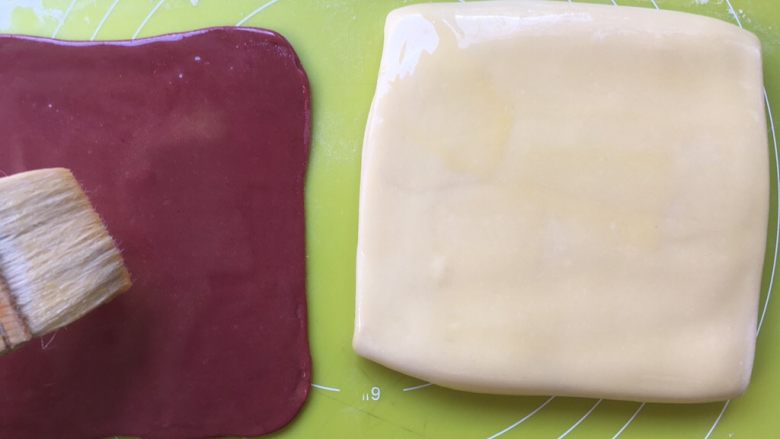 双色牛角酥,用毛刷在面片表层刷上一层黄油液，两色颜色的面片都刷 