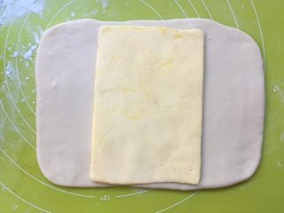 双色牛角酥,冰箱取出冷冻的黄油片，用刀裁开保鲜袋，将黄油片放在面片中间 