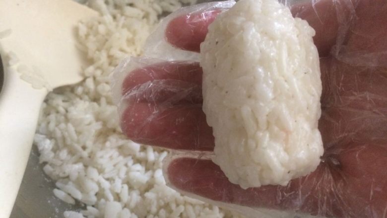 培根卷饭团,戴上干净手套，抓一把米饭捏成圆柱形饭团；