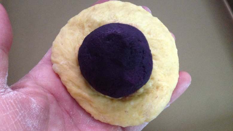  全麦紫薯南瓜面包,把松弛好的小面团擀成圆片包上紫薯馅，捏紧收口。