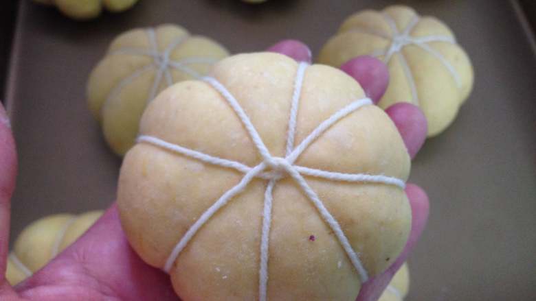  全麦紫薯南瓜面包,包好后用一条稍粗的棉线把面团均分成8份扎成如图状。