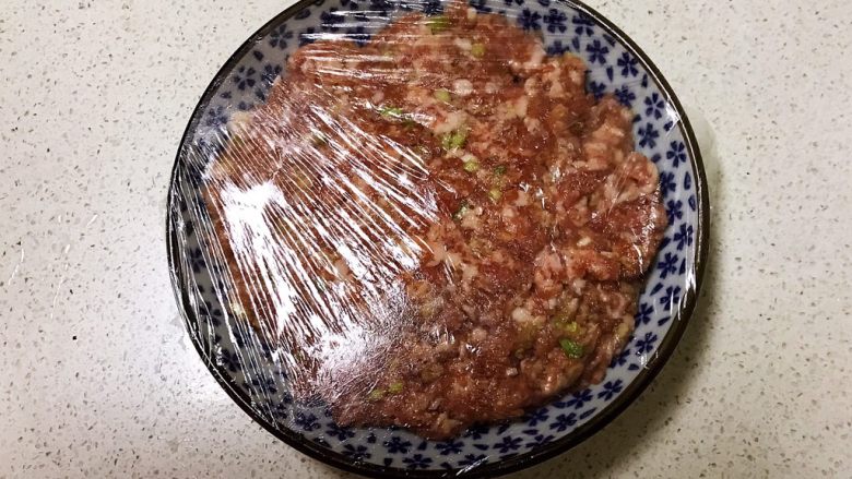 番茄汁焗茄盒,把调好的肉馅放入盘里，盖上保鲜膜，静止入味15分钟