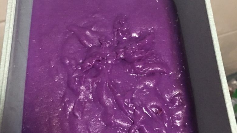 紫薯牛奶小方,8️⃣ 容器底部事先铺一层<a style='color:red;display:inline-block;' href='/shicai/ 630'>椰蓉</a>，立即加入煮好的紫薯泥，震荡，使表面平整。（我就是加得晚了，表面不怎么平整了。这里最好用方正的容器，做紫薯小方切块比较好看） 盖上盖子或者保鲜膜，放入冰箱冷藏3小时以上。