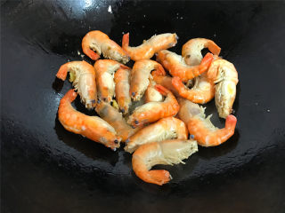 家常红烧大虾,把清洗干净的大虾沥干水份，放入锅中，爆至两面都呈金黄色。