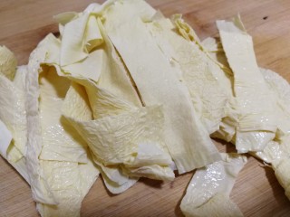 牛肉丝炒油豆皮,将整张的油豆皮儿放在案板上，切成条。