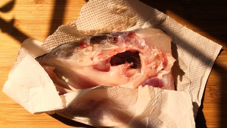 十味  鱼头豆腐汤,把腌制好的鱼头用清水多冲洗几次，用厨房纸把表面水份擦干。