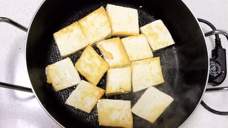 仔姜炒豆腐,炒锅烧热后刷一层大豆色拉油，放入豆腐块，煎至一面金黄就可以翻面，全程小火煎制