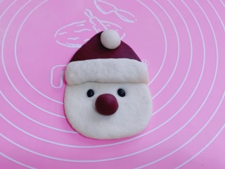 不一样的面食～圣诞老人馒头,把做好的白色小圆球放在帽子顶部、取一点红色面团做一个小圆球装饰圣诞老人的鼻子、两颗黑豆做眼睛！如图
